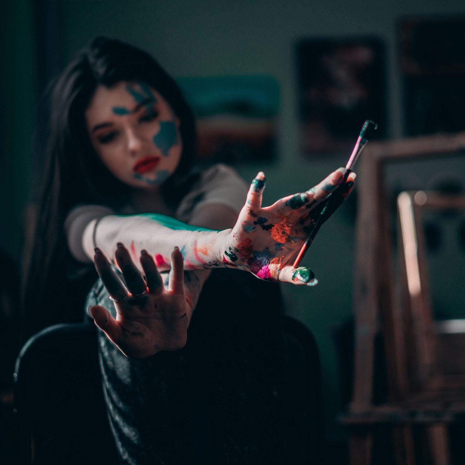Young woman artist showing creativity with colorful paint on hands in the studio.